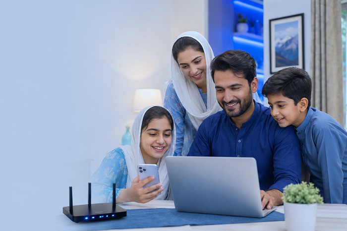 Pakistani family using a laptop and mobile phone with Rumi and Jojo home internet